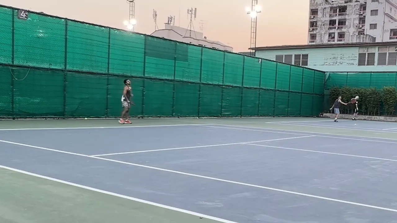 สนามเทนนิสกลางแจ้งที่มีผู้เล่นสองคนกำลังตีโต้กัน