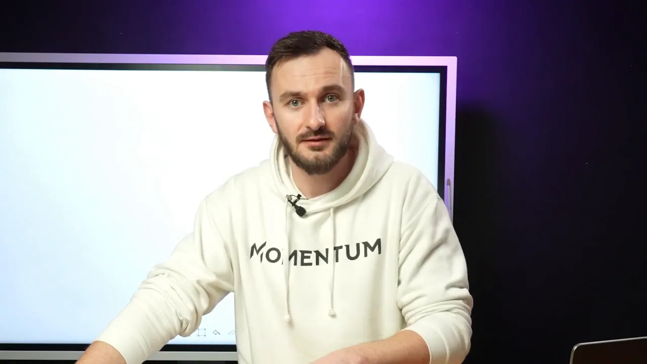 Presenter looking directly at the camera summarizing key points in front of a whiteboard